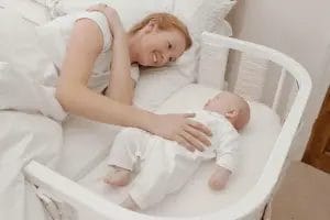 Maman avec bébé dans un lit cododo